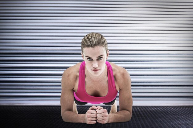 Image composite d'une femme musclée sur une position de planche