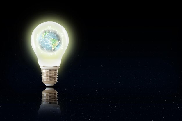Image composite numérique d'une ampoule éclairée avec la planète Terre sur un fond noir