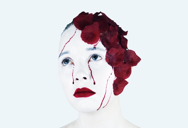 Image composite numérique d'une femme triste avec des pétales de rose rouge sur un fond blanc