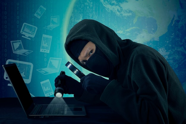 Image composite numérique d'un pirate informatique tenant une lampe flash éclairée et une loupe