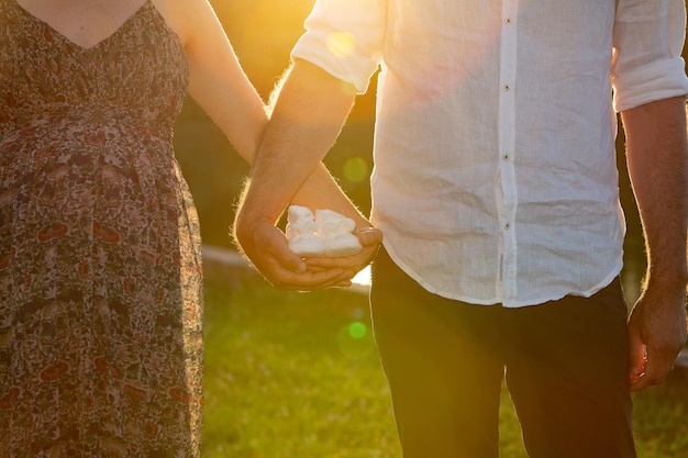 Image conceptuelle du genre révélée contre l'homophobie Couple attendant la naissance de leur fille avec des chaussures blanches pour bébé à la main