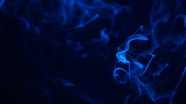 Image conceptuelle de la fumée de couleur bleue isolée sur fond noir foncé