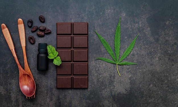 Image conceptuelle de nourriture de feuille de cannabis avec du chocolat noir et une fourchette sur fond de béton foncé.