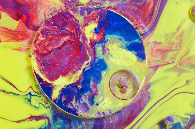 Image de couleurs rouge, jaune et bleu sur une surface liquide avec de minuscules orbes et des motifs circulaires