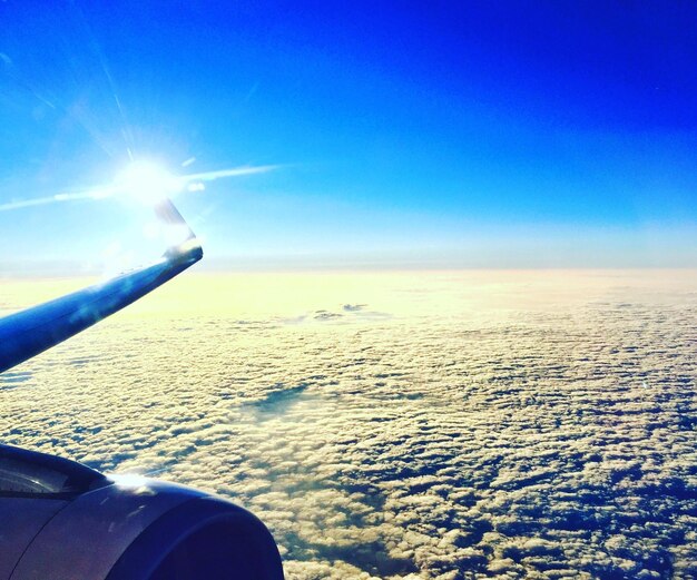 Image coupée d'un avion au-dessus d'un paysage nuageux contre un ciel bleu