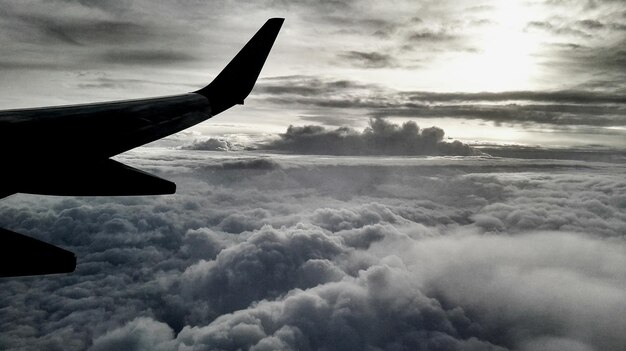 Photo image coupée d'un avion au-dessus d'un paysage nuageux
