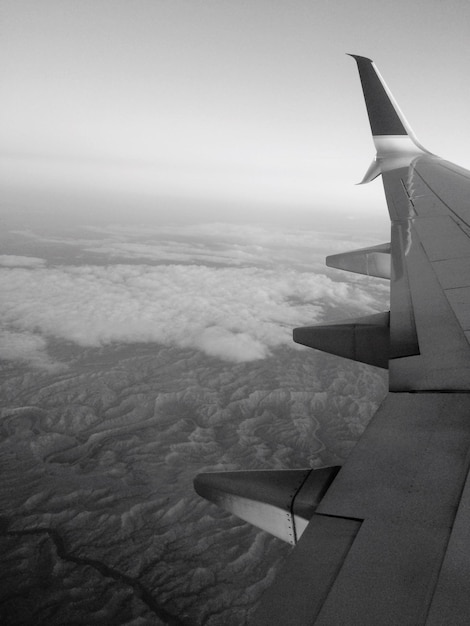 Photo image coupée d'un avion volant au-dessus du paysage contre un ciel dégagé