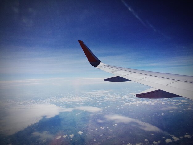 Photo image coupée d'un avion volant au-dessus d'un paysage nuageux