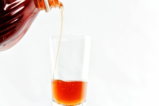 Photo image coupée d'une bouteille versant une boisson dans un verre sur un fond blanc