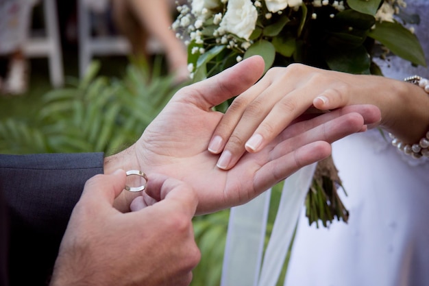 Image coupée d'un couple de mariés se tenant la main pour la cérémonie de l'anneau