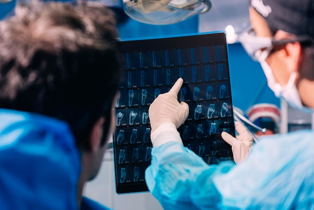 Image coupée d'un dentiste montrant des rayons X à un patient masculin dans une clinique
