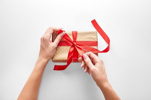 Image coupée d'une femme attachant un ruban à Noël présent sur un fond blanc