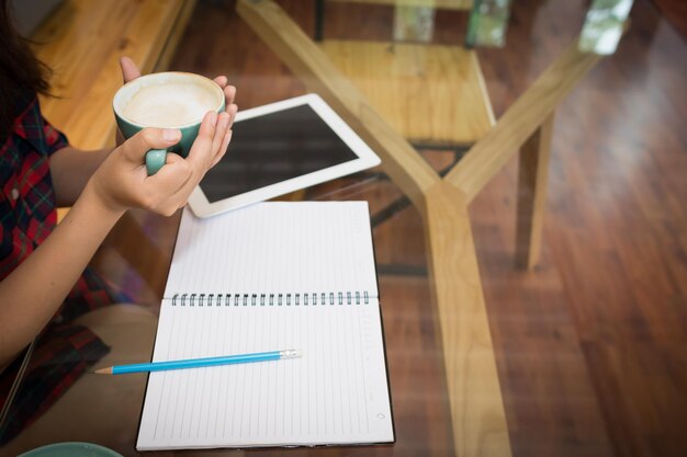 Photo image coupée d'une femme tenant une tasse de café à la table