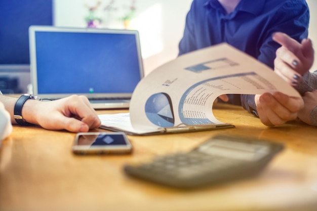 Image coupée de gens d'affaires discutant de données à table au bureau