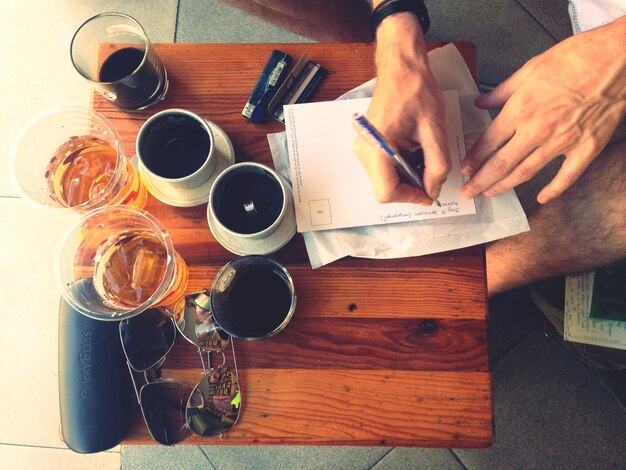 Photo image coupée d'un homme écrivant sur du papier en buvant du café