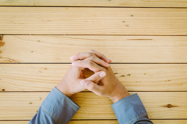 Photo image coupée d'un homme les mains serrées sur une table en bois