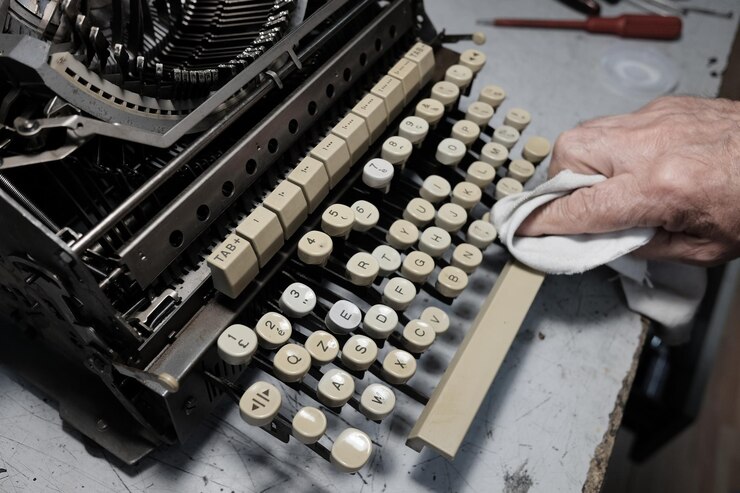 Photo image coupée d'un homme nettoyant une machine à écrire sur une table