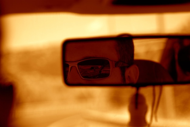 Photo image coupée d'un homme réfléchissant sur le rétroviseur d'une voiture