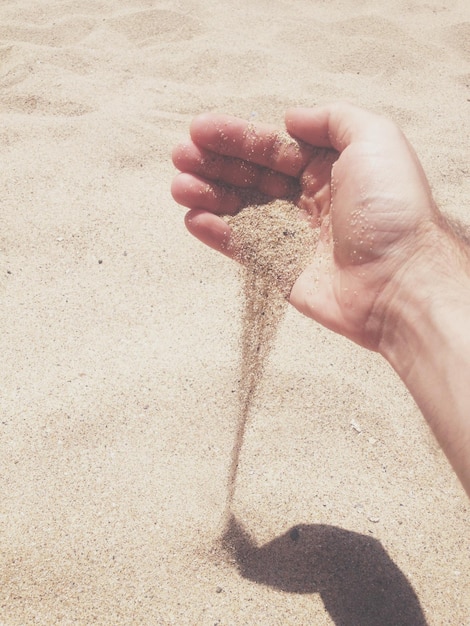 Photo image coupée d'un homme versant du sable sur la plage