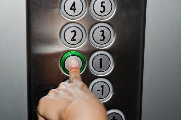 Image coupée d'une main appuyant sur un bouton dans un ascenseur