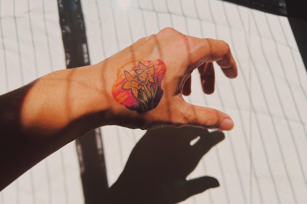 Image coupée d'une main tatouée contre le sol