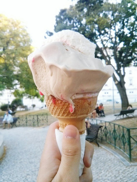 Photo image coupée d'une main tenant une crème glacée dans un parc