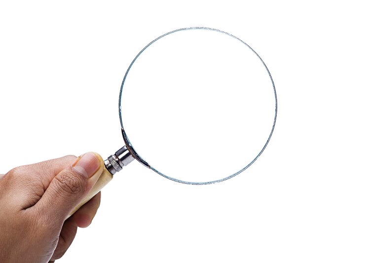 Photo image coupée d'une main tenant une loupe sur un fond blanc