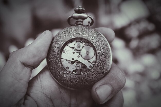 Photo image coupée d'une main tenant une montre de poche antique