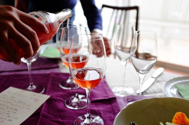Photo image coupée d'une main versant du vin dans un verre sur la table