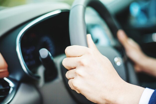 Image coupée de mains au volant d'une voiture