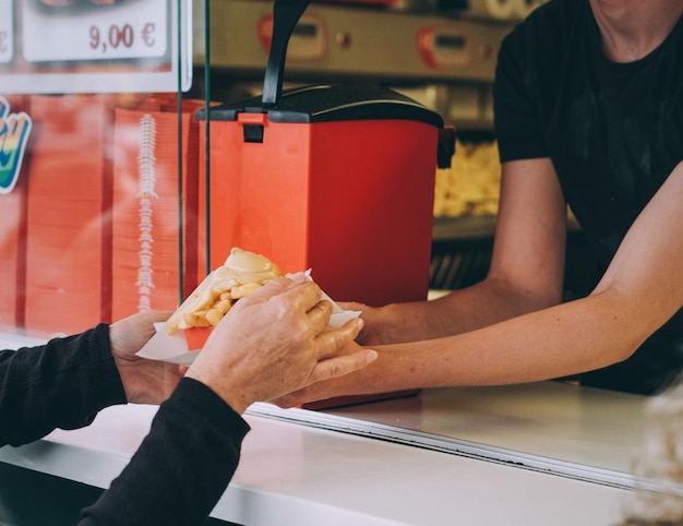 Photo image coupée de mains de clients achetant des frites à un homme.