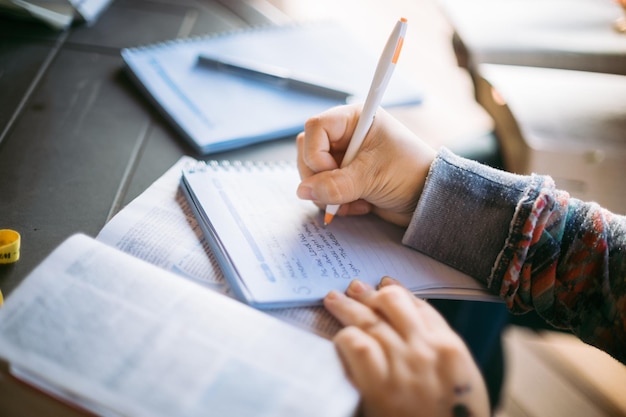 Image coupée de mains écrivant sur un livre