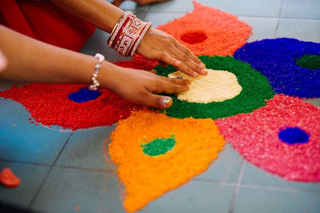 Image coupée de mains faisant du rangoli sur un sol en carreaux