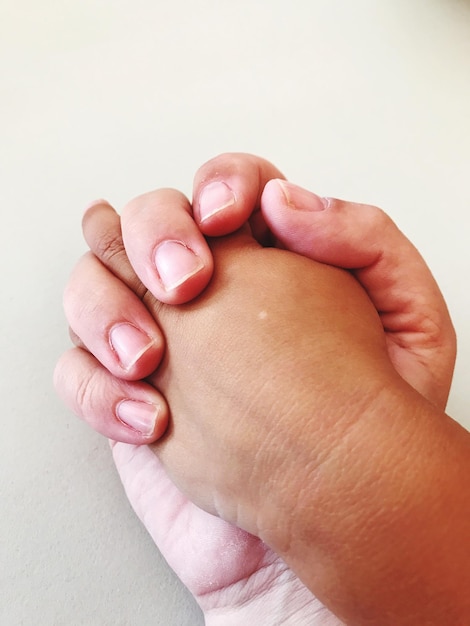 Photo image coupée d'un parent et d'un enfant se tenant par la main sur un fond gris