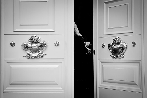 Photo image coupée d'une personne dans une chambre noire vue à travers une porte ouverte blanche