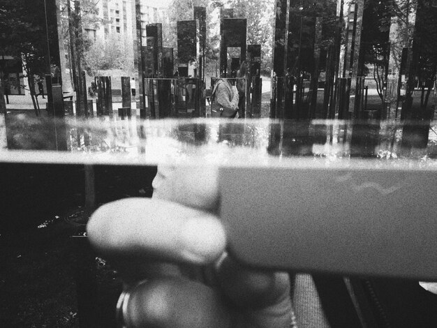 Photo image coupée d'une personne photographiant une fenêtre en verre avec une réflexion sur la ville