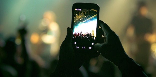 Image coupée d'une personne photographiant lors d'un concert de musique