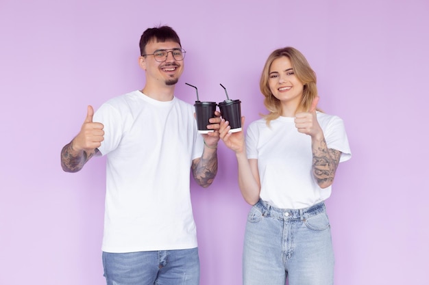 Image d'un couple de contenu homme et femme en vêtements en denim souriant tout en tenant des tasses à café à emporter