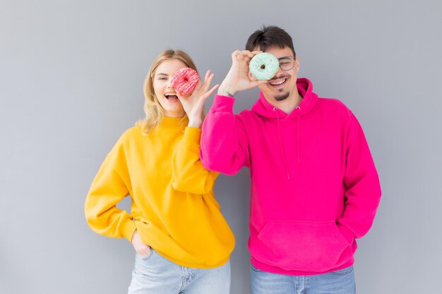 Image d'un couple excité homme et femme souriant tout en tenant des beignets sucrés