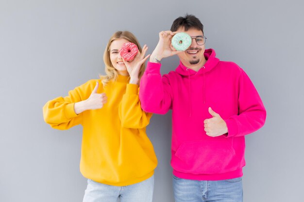 Image d'un couple excité homme et femme souriant tout en tenant des beignets sucrés