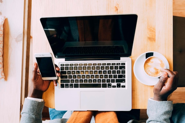 Image découpée d'un homme d'affaires utilisant un ordinateur portable pendant qu'il prend du café à la table