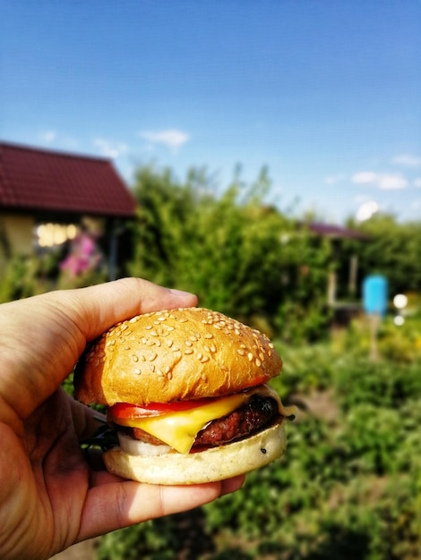 Photo image découpée d'une personne tenant un cône de hamburger contre le ciel