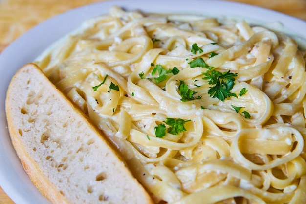 Image de délicieux et frais fettuccini italien traditionnel alfredo avec du pain et du persil