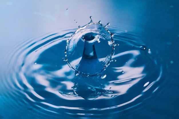 Image de deux gouttes d'eau entrant en collision sur une surface bleue propre