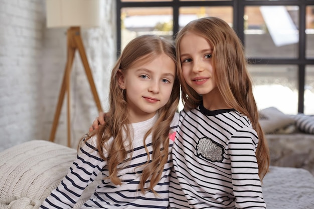 L'image de deux petites soeurs assises sur le lit dans la chambre