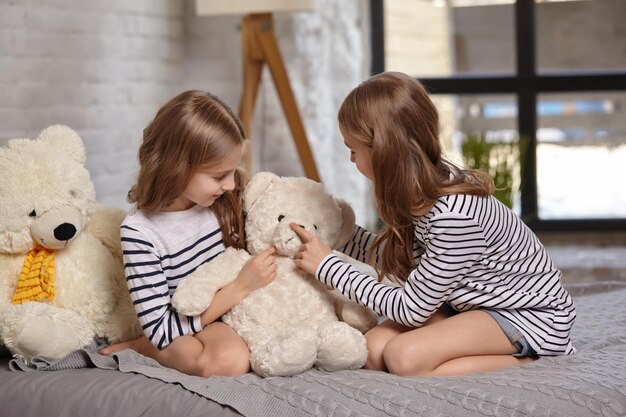 L'image de deux petites soeurs assises sur le lit dans la chambre