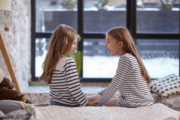 L'image de deux petites soeurs assises sur le lit dans la chambre