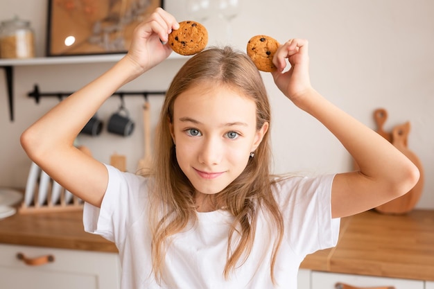 Image de deux soeurs filles heureuses à la cuisine à l'intérieur mangent un petit déjeuner ensemble jouent aux cookies Photo de haute qualité