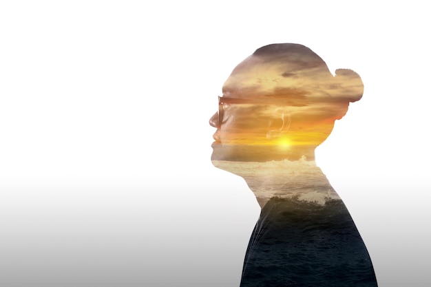 Image à double exposition d'un jeune homme et d'un coucher de soleil sur l'océan