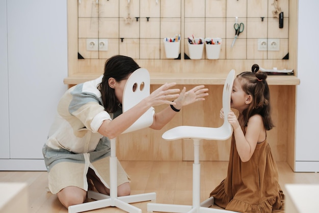 Image drôle de mère et fille jouant à travers les trous dans les selles